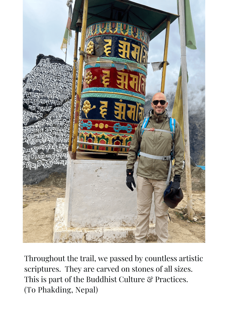 Mohamed Isa beside a large prayer wheel and carved stone on the way to Phakding